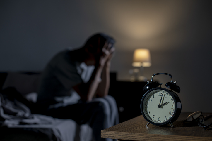 Depressed man sitting in bed cannot sleep from insomnia